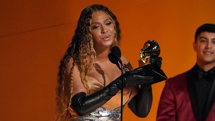 Das Foto vom 5. Februar 2023 zeigt die Sängerin Beyoncé bei den 65. Grammy Awards. Sie hält einen goldenen Grammy in den Händen, die bis über den Ellbogen in schwarzen Handschuhen stecken, und spricht in ein Mikrofon.