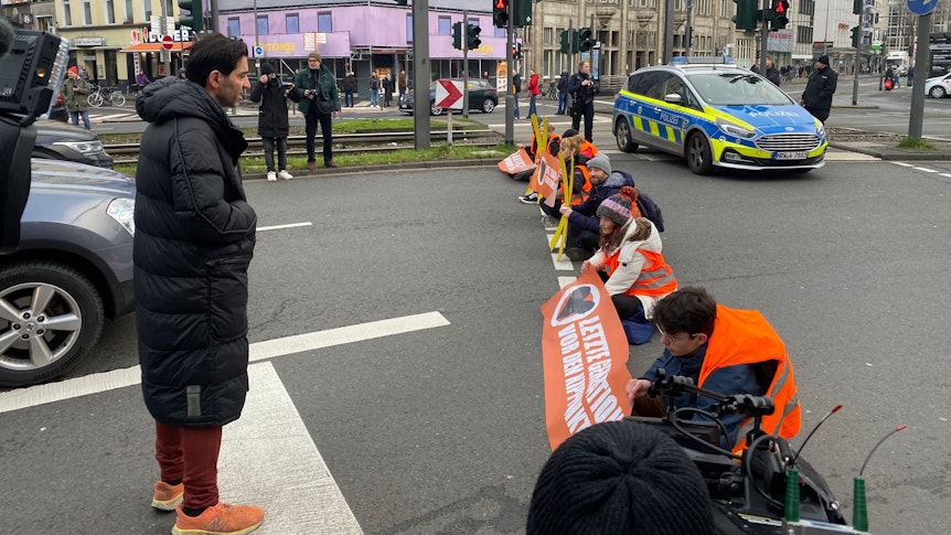 Ein Autofahrer sucht beim Protest in Köln das Gespräch mit der Letzten Generation.