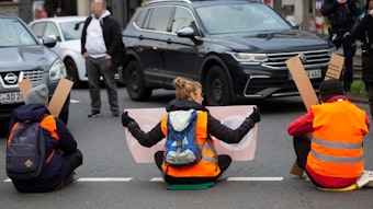 Klimaaktivisten kleben sich auf der Straße in Köln am Neumarkt fest.