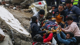 Nach dem verheerenden Erdbeben in der Nacht vom 5. auf den 6. Februar 2023 bergen Rettungskräfte und weitere Helfer auf einer Bahre einen Menschen aus einem eingestürzten Gebäude in Adana (Türkei).
