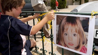 Ein kleiner Junge vor dem Bild der vermissten Maddie McCann.