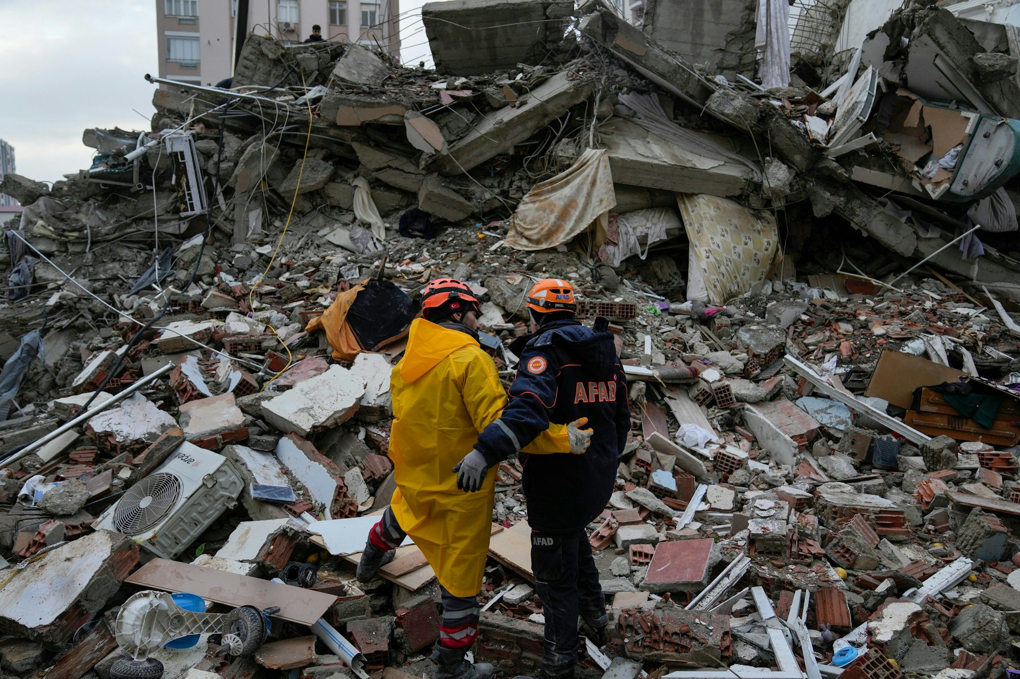 Türkei, Adana: Mitglieder eines Notfallteams halten einen Moment inne, während sie in einem zerstörten Gebäude nach Menschen suchen.