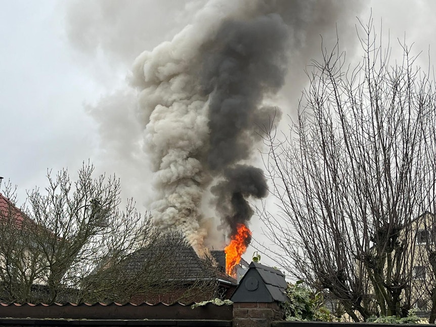 Aus einem Dachstuhl schlagen Flammen und eine Rauchsäule steht über dem Haus.