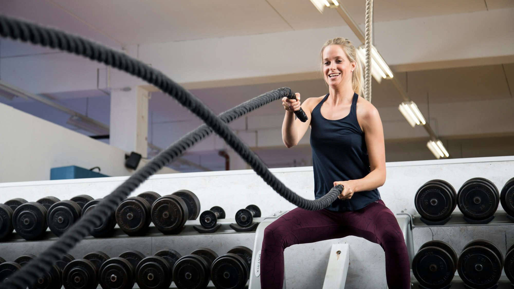 Im Fitnessstudio trainiert eine Frau mit zwei Seilen.