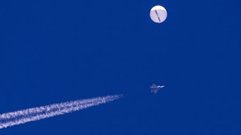 Ein großer Ballon schwebt über dem Atlantischen Ozean vor der Küste von South Carolina. Darunter sind ein Kampfjet und seine Kondensstreifen zu sehen.