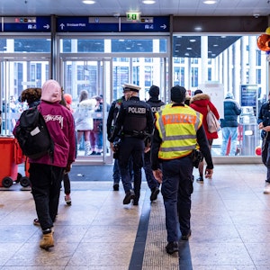 Polizisten gehen durch den Kölner Hauptbahnhof in Richtung Ausgang.