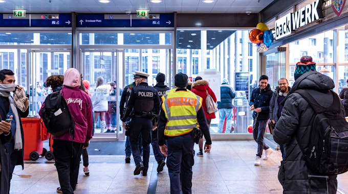 Polizisten gehen durch den Kölner Hauptbahnhof in Richtung Ausgang.