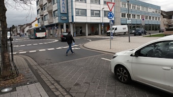 Ein Mann geht über einen Kreisverkehr, auf dem kein Weg für Fußgänger eingezeichnet ist.
