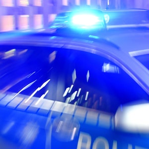 Ein Streifenwagen der Polizei steht mit eingeschaltetem Blaulicht auf der Straße.