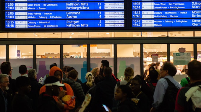 Menschen warten im Hauptbahnhof vor der Anzeigetafel, auf der zahlreiche Zugverspätungen angegeben werden.