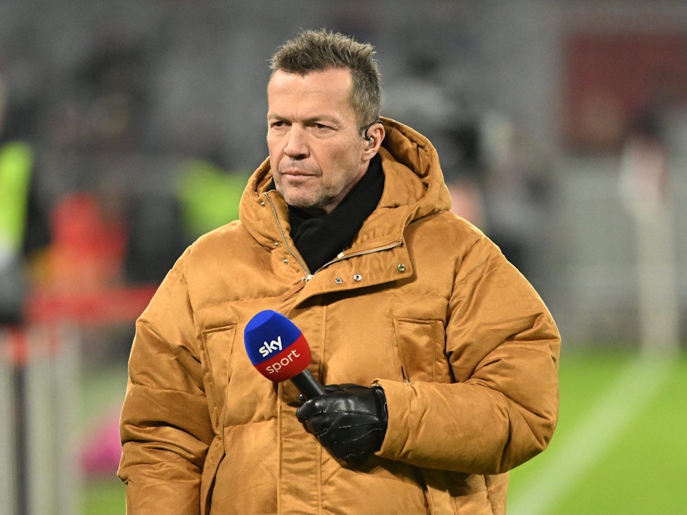 Lothar Matthäus steht in einer Winterjacke und einem Sky-Mikrofon in der Allianz Arena.