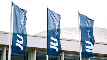 Drei Flaggen der Jungen Union stehen vor einem Gebäude.