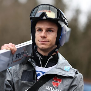 Andreas Wellinger (Deutschland) kommt zum Training in Bischofshofen. Er trägt einen Helm mit hochgezogener Skibrille und eine Trainingsjacke. Seine Skier trägt er auf der rechten Schulter.