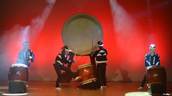Mehrere Männer spielen Trommel auf einer Bühne.