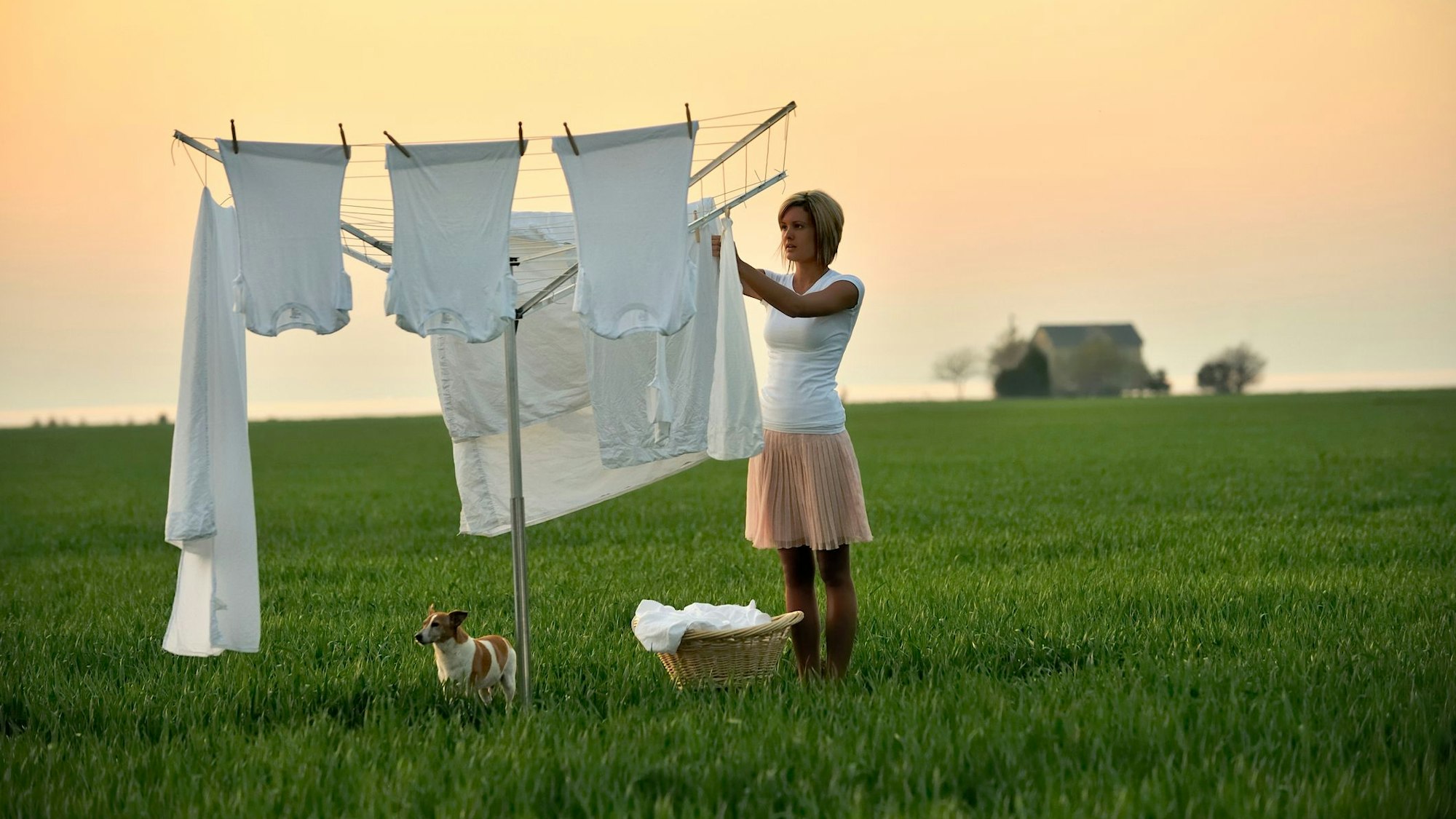 Eine Frau hängt Wäsche auf eine Wäschespinne.