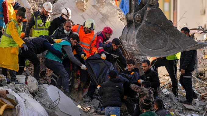 07.02.2023, Türkei, Adana: Mitglieder eines Rettungsteams tragen den Körper einer Person, die in den Trümmern eines zerstörten Gebäudes gefunden wurde. Rettungskräfte suchen weiterhin nach Überlebenden in den Trümmern tausender Gebäude, die durch ein starkes Erdbeben und mehrere Nachbeben, die die Osttürkei und das benachbarte Syrien erschütterten, eingestürzt waren.&nbsp;