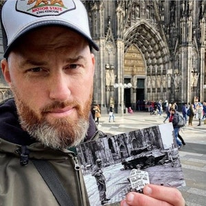 Ein Mann hält ein Foto vor dem Kölner Dom in der Hand.