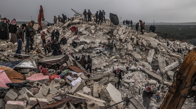 Rettungskräfte und Zivilisten suchen nach Menschen in den Trümmern eines zerstörten Gebäudes.