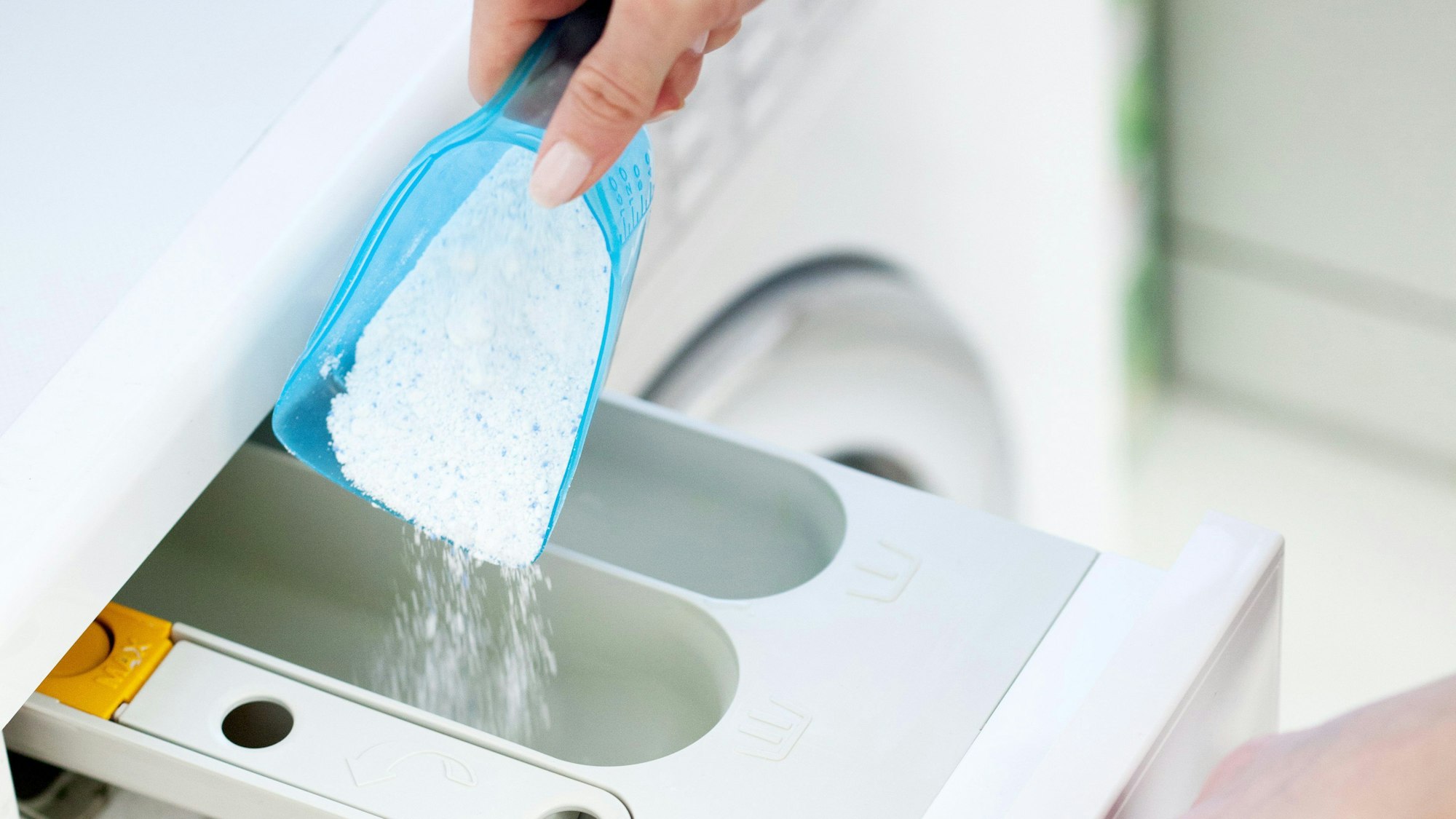Waschpulver wird in das Waschmittelfach einer Waschmaschine eingefüllt.