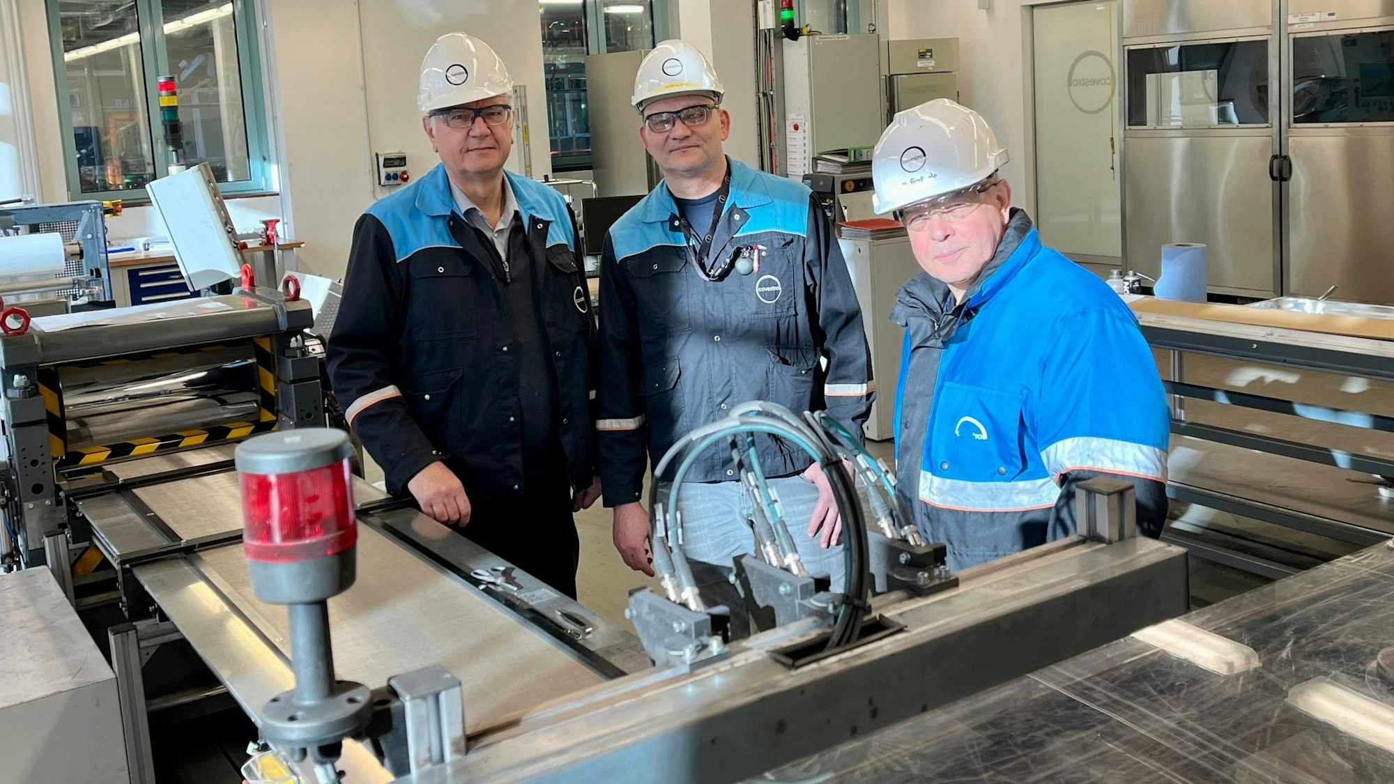 Andreas Bulan, Roberto Warthe und Michael Großholz von Covestro stehen an einer selbst konstruierten Anlage, auf der Sauerstoff-Verzehrkathoden gebaut werden.