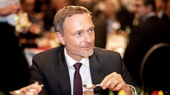 Christian Lindner (FDP), Bundesfinanzminister, hält beim "Defftig Ollnborger Gröönkohl-Äten" einen Ammerländer Löffeltrunk in den Händen.