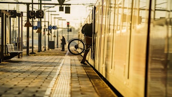 Ein Bahnreisender hebt sein Fahrrad in eine S-Bahn.