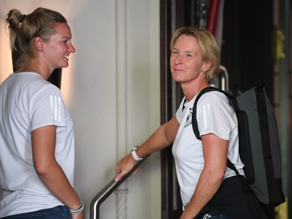 Fußball-Nationalspielerin Alexandra Popp lacht Bundestrainerin Martina Voss-Tecklenburg an.