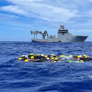 Auf diesem Foto der neuseeländischen Polizei schwimmt eine Ladung Kokain auf der Oberfläche des Pazifischen Ozeans, dahinter das Schiff HMNZS Manawanui der Royal New Zealand Navy.