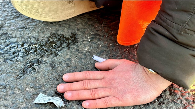 Eine Klimaaktivistin hat sich mit einer Hand auf einer Hauptverkehrsstraße  festgeklebt.
