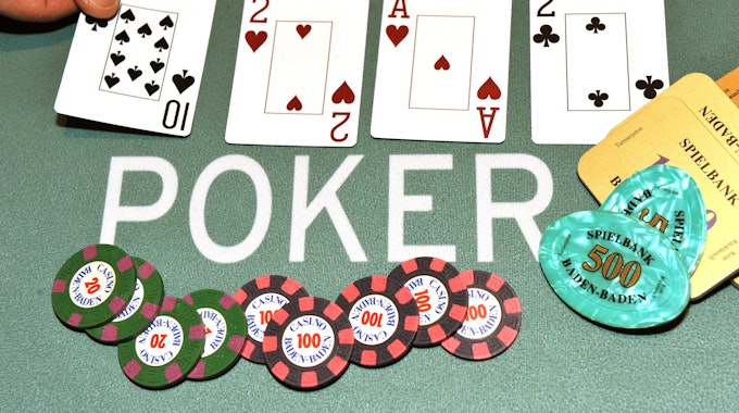 Ein Dealer legt bei einem Pokerspiel die Pokerkarten auf den Tisch.