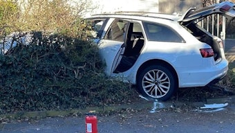 Das Bild zeigt ein weißes Auto, das nach einem Unfall in einer Heck steht.