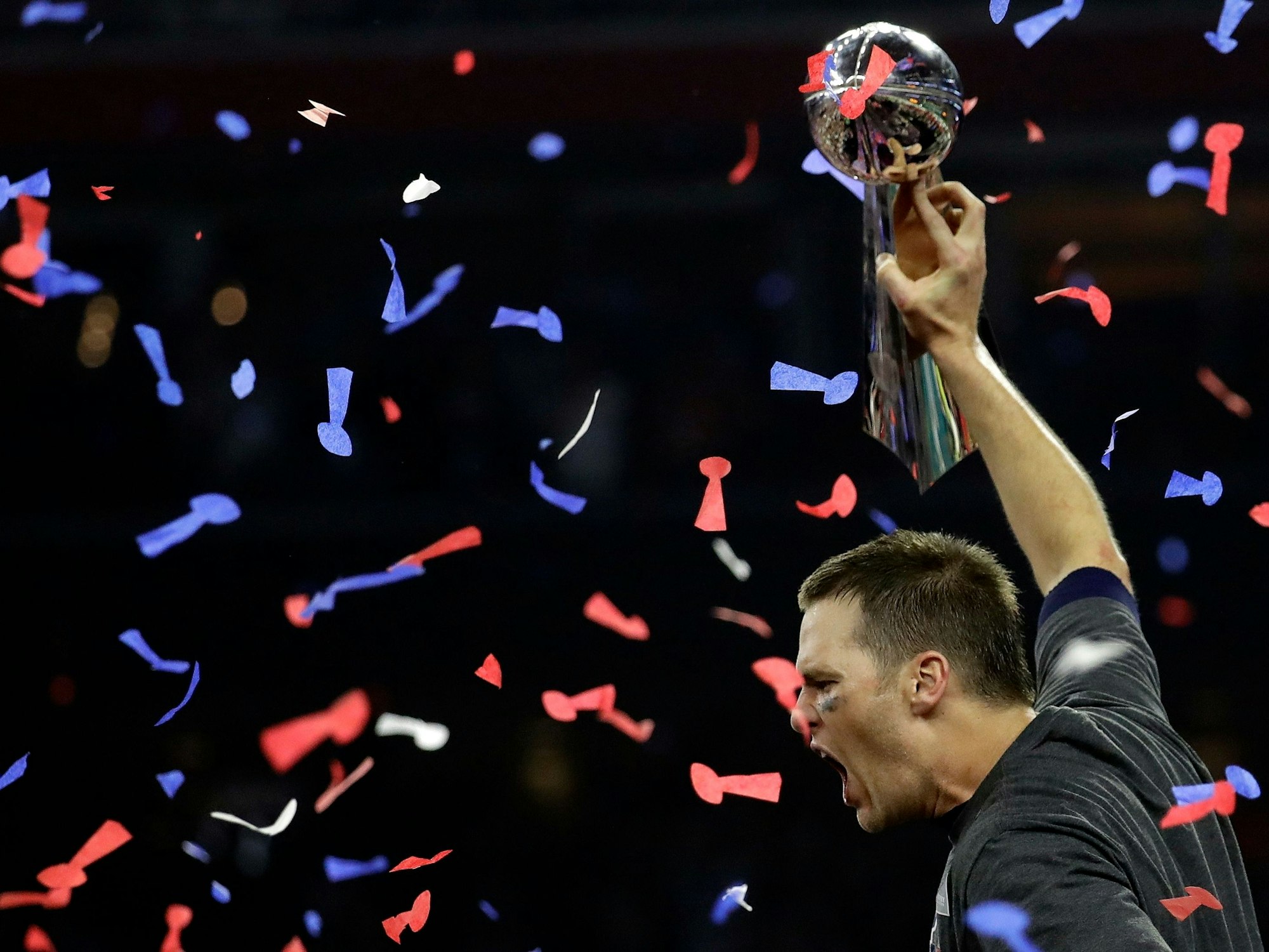 Tom Brady brüllt und streckt die Vince Lombardi Trophy in die Luft.