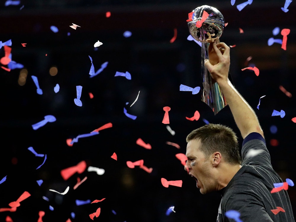 Tom Brady brüllt und streckt die Vince Lombardi Trophy in die Luft.