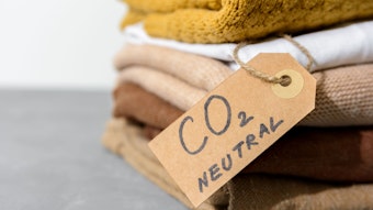 Mehrere Wollpullover liegen gefaltet auf einem Stapel. Daran hängt ein Schild mit der Aufschrift: "CO₂-neutral".