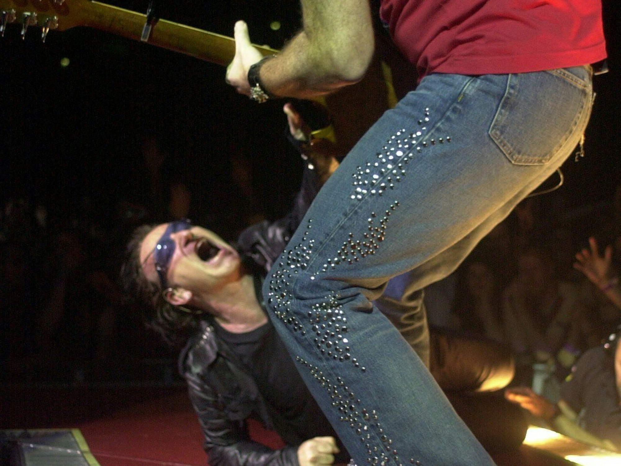 Der Sänger Bono performt auf dem Boden der Bühne in der Kölner Lanxess-Arena beim Auftritt seiner Band U2 im Juli 2001.