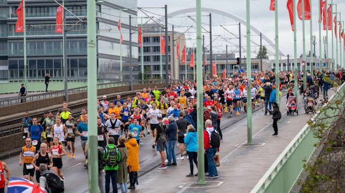 Etliche bunt gekleidete Läuferinnen und Läufer überqueren die Deutzer Brücke.
