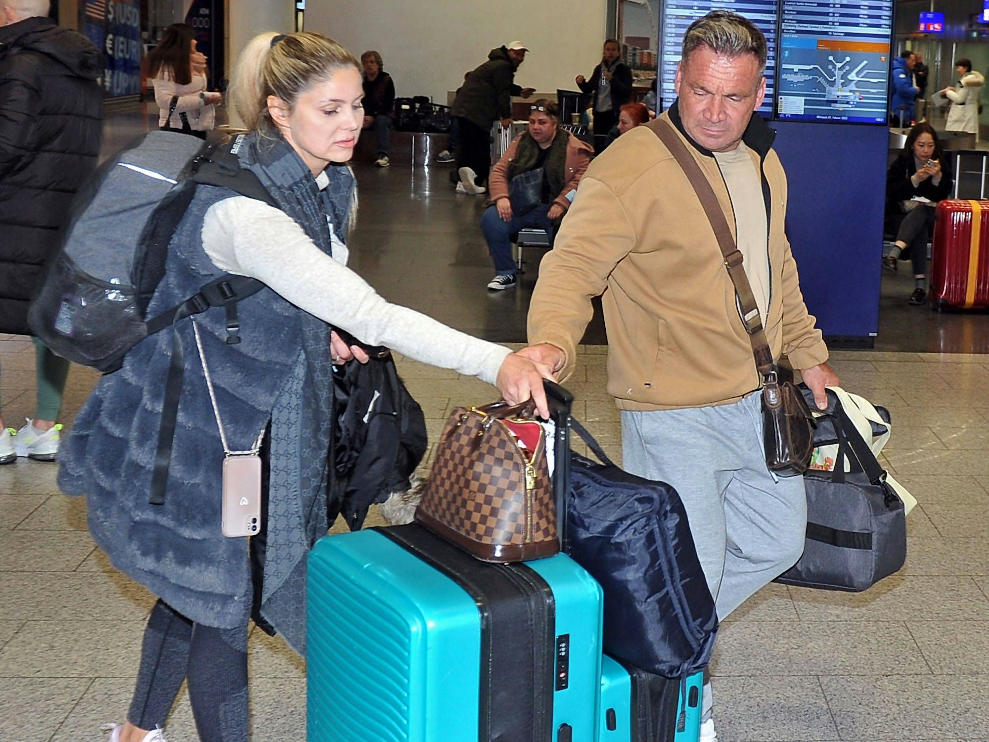 Das Foto zeigt Realiy-Darsteller Peter Klein (m.) und Schauspielerin Yvonne Woelke (l.) am Flughafen in Frankfurt am Main.