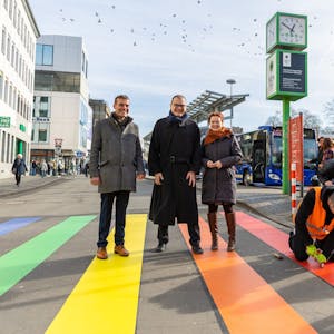 Zu sehen ist ein Straßenübergang in Bonn. Die Zebrastreifen sind regenbogenfarben.