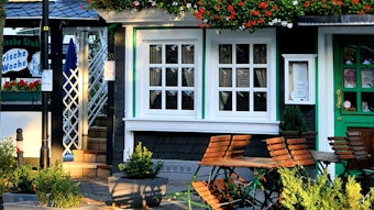 Foto eines Gasthauses in Burscheid mit Blumen und Biergartenstühlen.