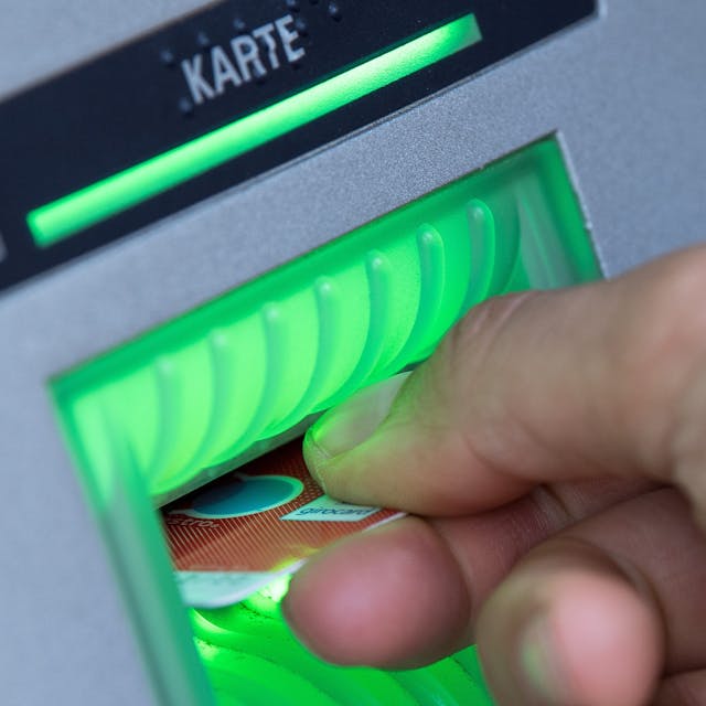 Eine Bankkundin steckt ihre Girokarte in einen Geldautomaten.