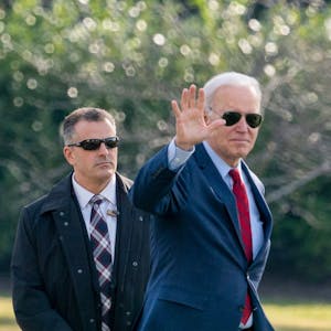 Präsident Joe Biden trägt eine Sonnenbrille und winkt in die Kamera.&nbsp;