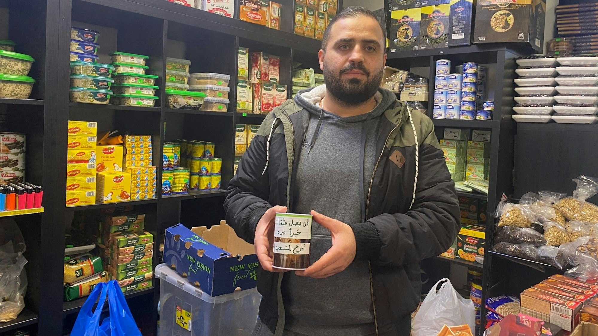 Das Foto zeigt Ammar Mdeek mit einer Spendendose. Der Syrer sammelt in seinem Lebensmittelgeschäft an der Brühler Uhlstraße Spenden für die Erdbeben-Opfer in seiner Heimat.