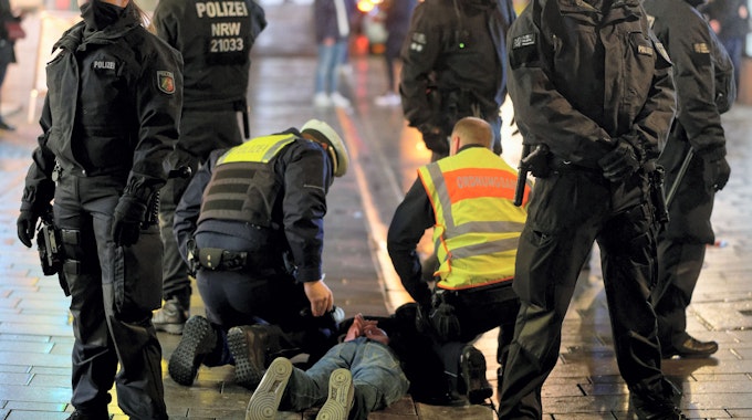 Mitarbeiter des Ordnungsamtes und der Polizei halten in der Altstadt einen bei einer Kontrolle Geflüchteten auf dem Boden fest.