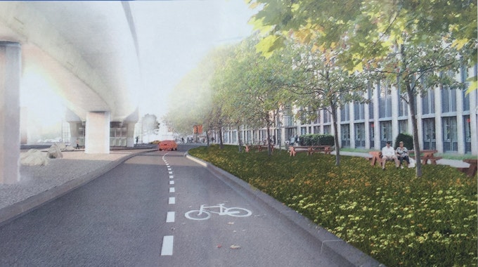 Ein Fahrstreifen mit dem Piktogramm für Radfahrer ist zu sehen. Links sind die Stelzen der Hochbahn, rechts ein Grünstreifen, dahinter ein Gebäude.