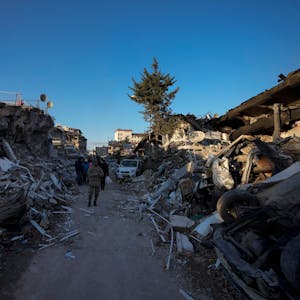 Ein Mann geht inmitten zerstörter Gebäude. In den Erdbeben-Gebieten in Syrien und der Türkei werden bei der Suche nach Verschütteten immer mehr Leichen aus den Resten eingestürzter Gebäude geborgen.