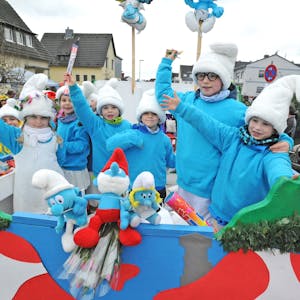 Als Schlümpfe verkleidete Kinder stehen auf einem Karnevalswagen.