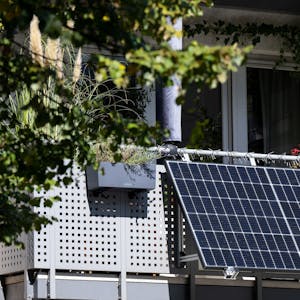 Eine kleine Solaranlage ist an einem Balkon eines Mehrparteienhauses angebracht.