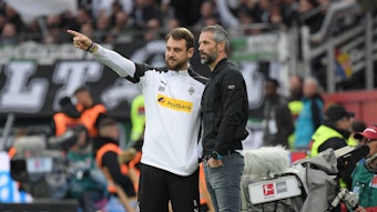 René Maric (l.) und Marco Rose stehen in der Coaching-Zone der BayArena in Leverkusen beim Bundesliga-Spiel von Borussia Mönchengladbach bei Bayer am 2. November 2019. Maric zeigt mit seinem rechten Zeigefinger nach vorne, Rose schaut zu.