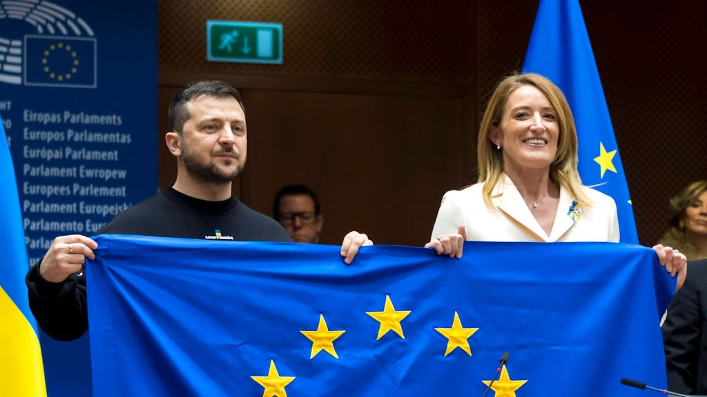 Der ukrainische Präsident und die Präsidentin des Europäischen Parlamentes halten gemeinsam die EU-Flagge hoch. Selenskyj und Metsola sehen die Zukunft der Ukraine in der EU.