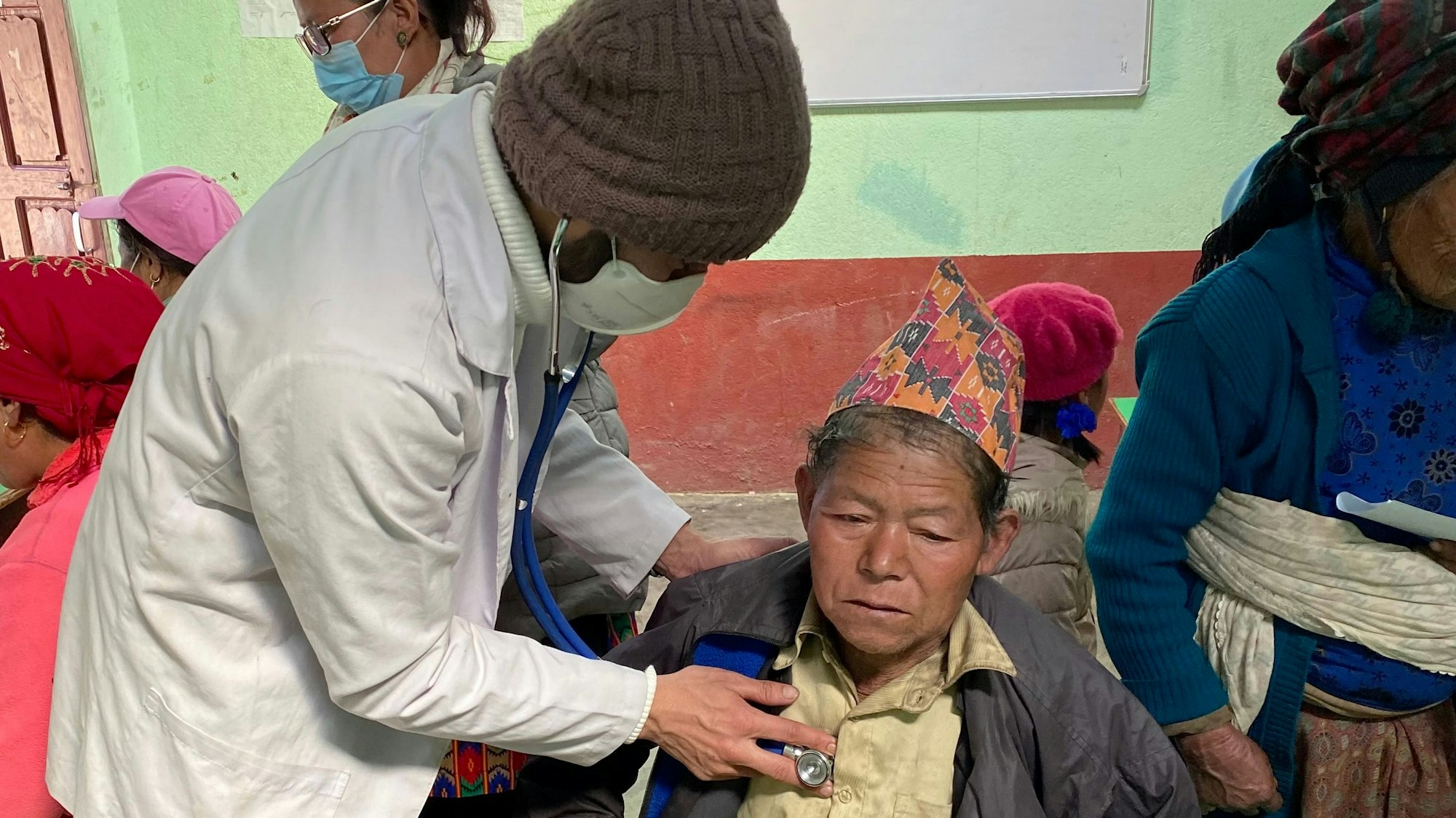 Ein Arzt horcht eine ältere Frau mit einem Stetoskop ab.